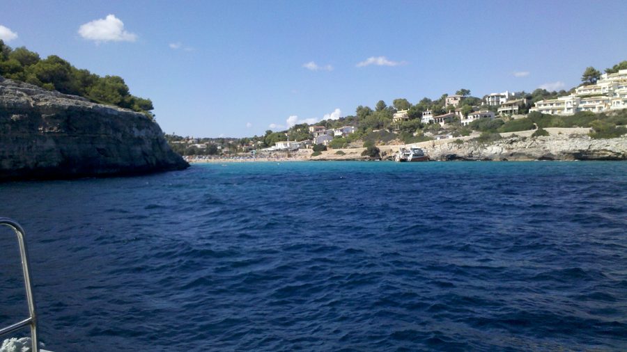 Cala Romantica beziehungsweise S'Estany d'en Mas von der Meerseite mit Sandstrand und felsigen Küstenflanken