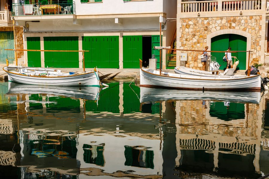 Spiegelung der Häuser und Boote im Hafen von Cala Figuera