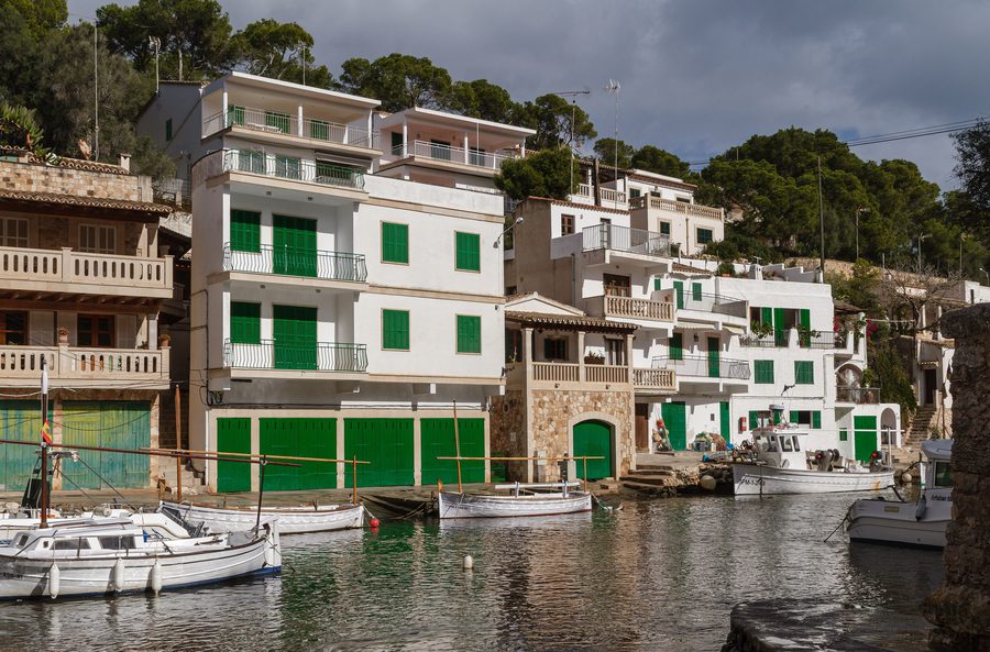 Fischerhäuser und Bootsgaragen am Wasserarm Caló d’en Busques in der Bucht von Cala Figuera